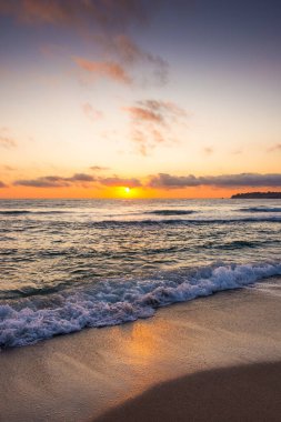 Golden Sunrise 'da kumlu sahilde dalgaların yaklaşması. Yazın Karadeniz 'de sozopol dolu sıcak bambu plajı. Güneş ufukta parlıyordu. seyahat arkaplanı için güzel düşük açılı dikey resim