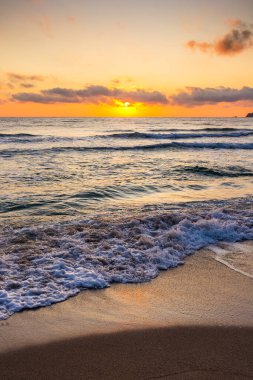 Golden Sunrise 'da kumlu sahilde dalgaların yaklaşması. Yazın Karadeniz 'de sozopol dolu sıcak bambu plajı. Güneş ufukta parlıyordu. seyahat arkaplanı için güzel düşük açılı dikey resim