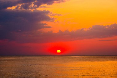 Denizde gün doğumunda dramatik bir gökyüzü. Duvar kağıdı için harika bir atmosferik arka plan. Suyun üstünde fırtınalı bulutlar. Güneş ufukta belirdi. Sozopol Körfezi 'nin yaz manzarası. ılık renkli bir eğilim