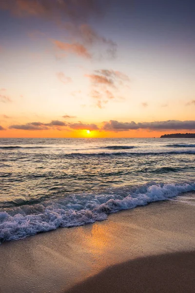 Golden Sunrise 'da kumlu sahilde dalgaların yaklaşması. Yazın Karadeniz 'de sozopol dolu sıcak bambu plajı. Güneş ufukta parlıyordu. seyahat arkaplanı için güzel düşük açılı dikey resim