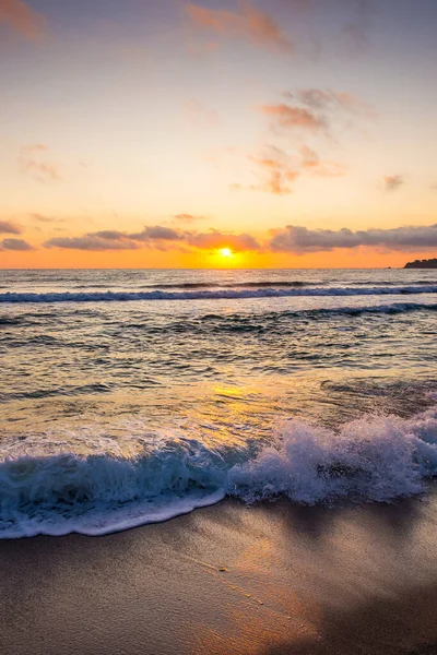 Golden Sunrise 'da kumlu sahilde dalgaların yaklaşması. Yazın Karadeniz 'de sozopol dolu sıcak bambu plajı. Güneş ufukta parlıyordu. seyahat arkaplanı için güzel düşük açılı dikey resim