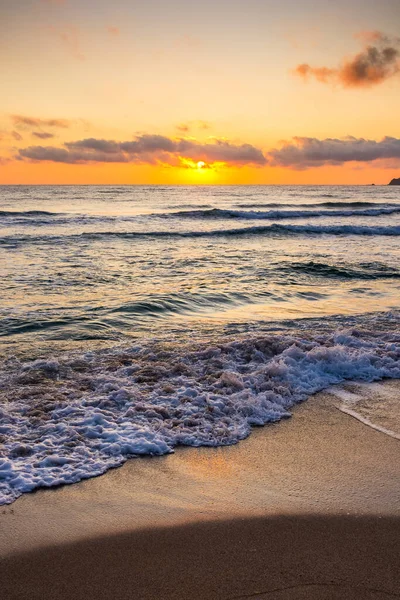 Golden Sunrise 'da kumlu sahilde dalgaların yaklaşması. Yazın Karadeniz 'de sozopol dolu sıcak bambu plajı. Güneş ufukta parlıyordu. seyahat arkaplanı için güzel düşük açılı dikey resim