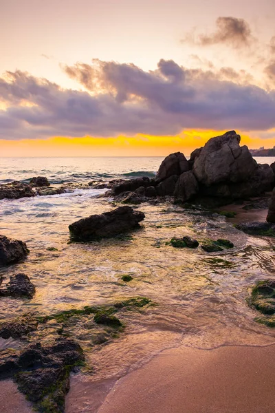 Şafak vakti kumlu ve taşlı Avrupa sahili. Bulgaria 'nın sabah güneşindeki güzel deniz manzarası. Romantik turuncu ışıltılı tatil geçmişi. Bulutlu dramatik gökyüzü