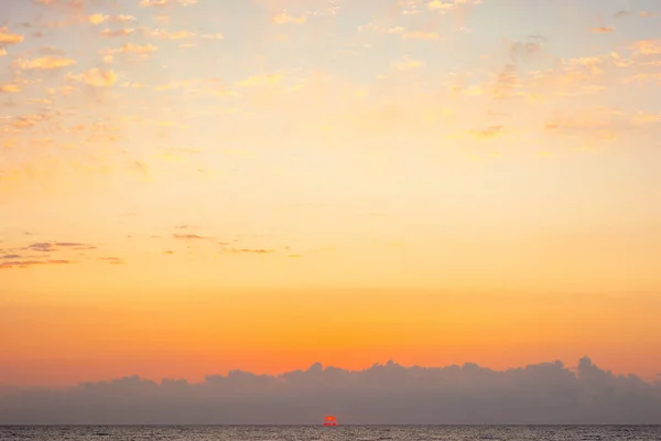 Turuncu bulutlu mavi gökyüzü. Gündoğumunda doğa arka planı. Denizin ufuklarında güneş