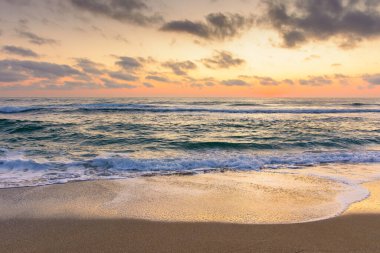 Deniz dalgası şafakta kumsala değecek. Sozopol 'da yaz tatili. Doğa, parlak turuncu gökyüzü ve kara bulutlar altında huzur dolu rüyalar. Sakin suyu olan deniz manzarası ve rahatlama havası.
