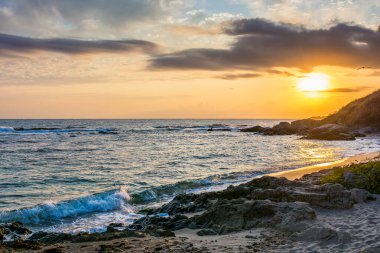Gündoğumunda Karadeniz kumlu sahilin manzarası. Bulgaria kıyısındaki altın kum ve kayalar. Güneşin ufukta göründüğü güzel bir manzara. Avrupa yaz tatili sezonu ve eğlence konsepti
