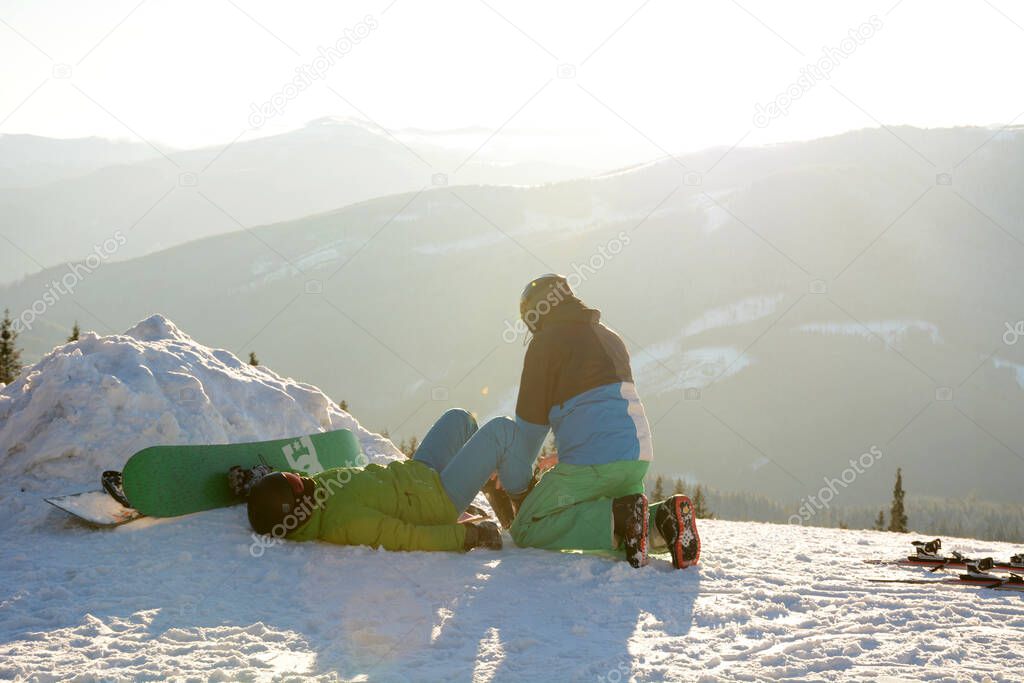 Skier examines the leg snowboarder, which lies on the snow after a fall in Carpathians, Bukovel