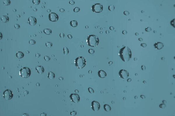 Rain drops on window glass. Natural blue water abstract background. Rainy day concept