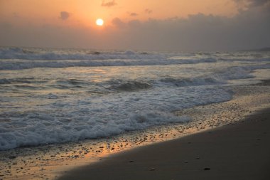 Denizde gün doğumu. Güneşli yol ve dalgalar. Bulutlardaki güneş. Yaz dönemi geçmişi. Georgioupolis plajı, Girit Yunanistan