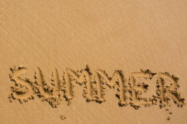 Kum plajı dokusu üzerine yaz kelimesi. Tasarım için doğal kum arkaplanı kopyalama alanı ile yakın plan. Yaz konsepti