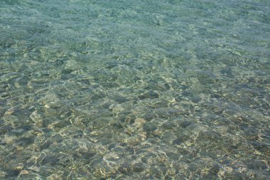 Parlak mavi deniz suyu arka planda dalgalanır, dalgalar ve parlar. Falasarna plajı, Girit Adası simgesi, Yunanistan