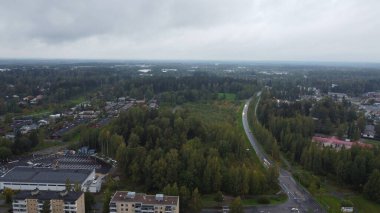 Sonbaharda bulutlu bir günde ağaçların, binaların ve yolların olduğu bir şehrin hava manzarası.