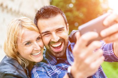 Gülümseyen çift selfie çekiyor.