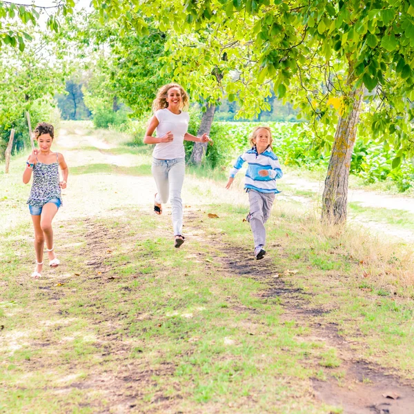 Donna con bambini che corrono in giardino — Foto Stock