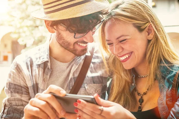 Sonriente pareja joven mirando el teléfono inteligente — Foto de Stock