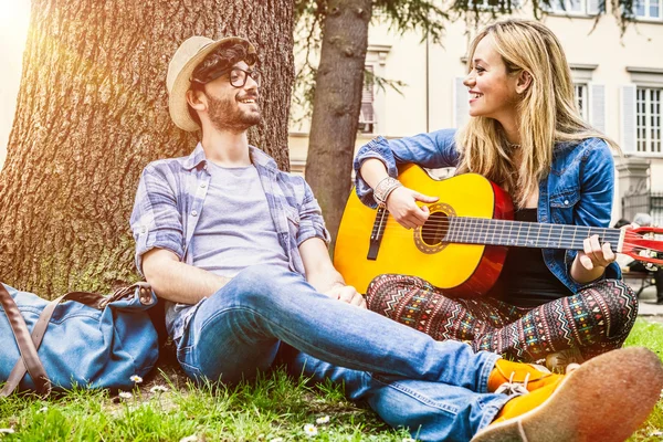 Feliz joven pareja sentado en la hierba — Foto de Stock