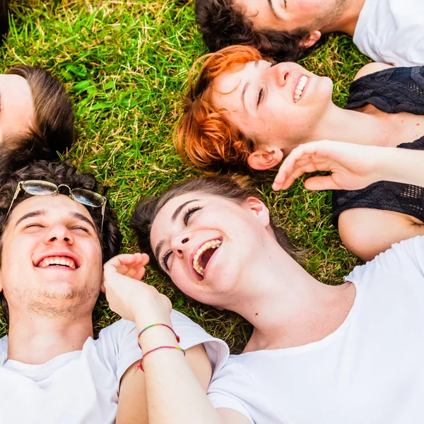 Amigos riendo y acostados en la hierba — Foto de Stock