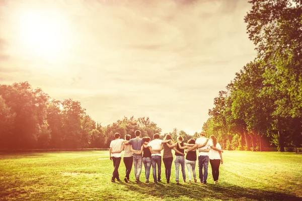 Vänner promenader i parken vid solnedgången — Stockfoto