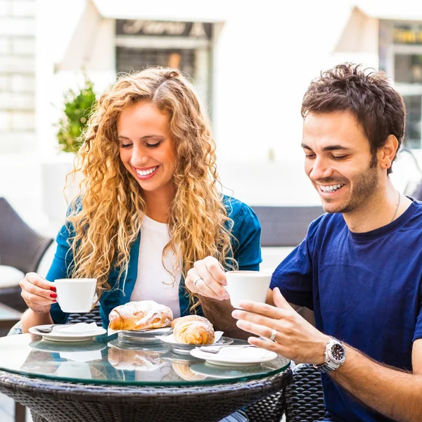 Couple drinking coffee and eating croissants