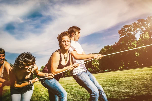 Amigos felices tirando de la cuerda juntos — Foto de Stock