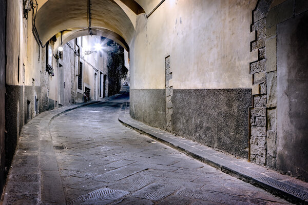 Old narrow illuminated city street in Florence at night, Toscana, Italy