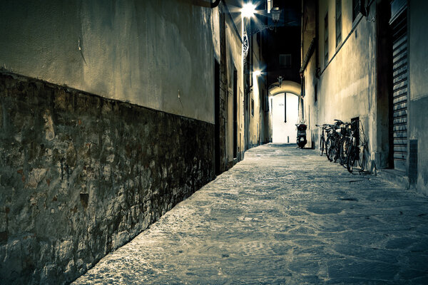 Old narrow illuminated city street in Florence at night, Toscana, Italy