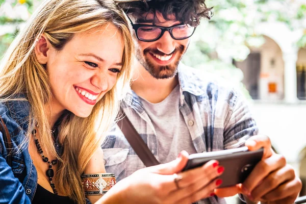 Sonriente pareja joven mirando el teléfono inteligente — Foto de Stock