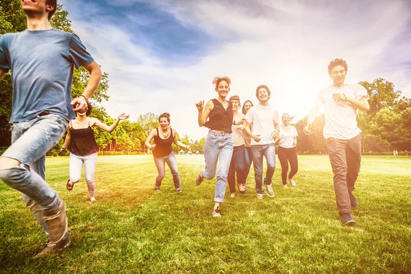 Grupo de amigos correndo no prado verde — Fotografia de Stock