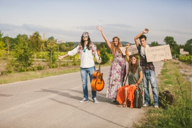 Hippies hitchhiking on the road with placards clipart