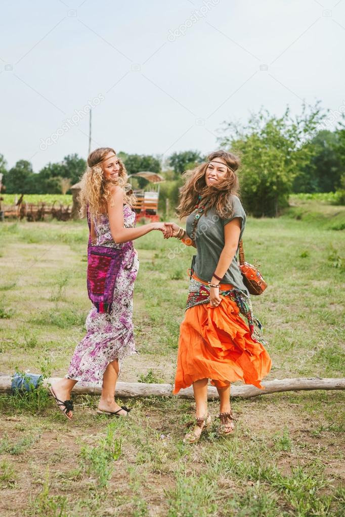 Girls in hippie style dancing on the meadow 