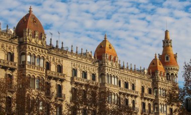 Karmaşık taş işçiliğinin, kemerli pencerelerin ve turuncu renkli kubbelerin yer aldığı çarpıcı bir Barcelona simgesi. Bu mimari cephe, ünlü bulvar boyunca tarihi cazibeyi, zarafeti ve kendine özgü tarzını yansıtıyor..