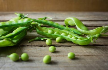 Ahşap zemin üzerinde kar bezelyesi yığını. Çin bezelyesi olarak da bilinen bezelyeler mükemmel C vitamini kaynakları ve iyi bir folik asit kaynağıdır..