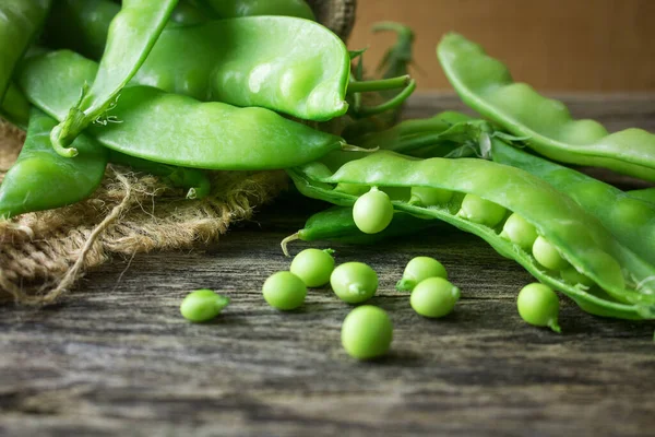 Pile of snow peas on wood background. Snow peas, also known as Chinese sugar peas, are excellent sources of vitamin C and a good source of folic acid.