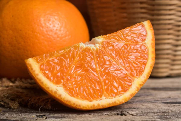 Fresh orange slice and whole orange on wooden table. Oranges are an excellent source of fiber and vitamin C. Antioxidants in oranges help protect skin from free radical damage and stop premature aging.