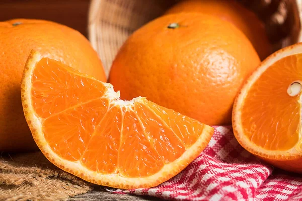 Fresh orange slice and whole orange on wooden table. Oranges are an excellent source of fiber and vitamin C. Antioxidants in oranges help protect skin from free radical damage and stop premature aging.