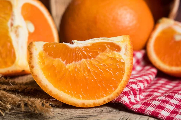 Fresh orange slice and whole orange on wooden table. Oranges are an excellent source of fiber and vitamin C. Antioxidants in oranges help protect skin from free radical damage and stop premature aging.