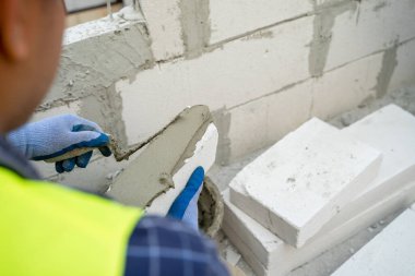 İnşaat işçisi yeni eve tuğla duvar örüyor..