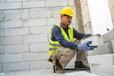 Construction worker builds a brick wall in the new house. clipart