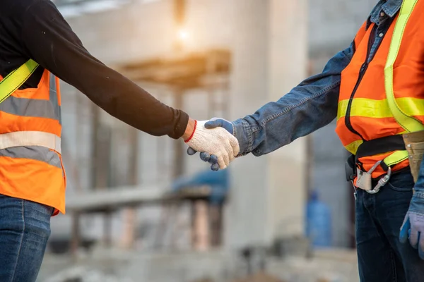 建設現場で握手を交わして挨拶する2人のエンジニアのビルダーの手を閉じる — ストック写真