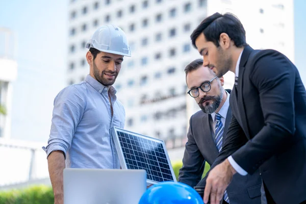 İki işadamı, ofis binası önünde yenilenebilir enerji güneş panelleri hakkında konuşuyor..