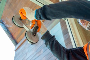 İnşaat işçileri yeni bir binaya pencere kuruyor, elleri cam cam cam taşımak için özel bir alet tutuyor.. 