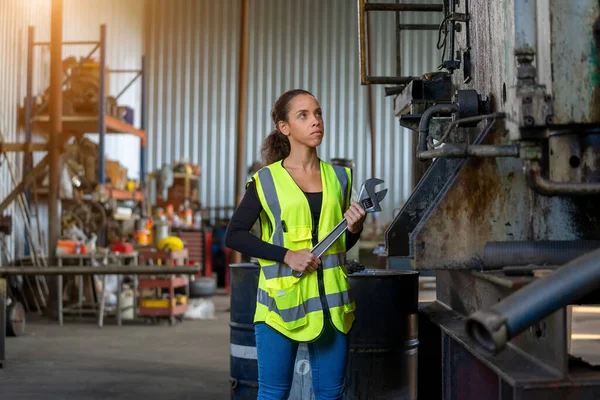 Engineer women in protective uniform doing practical work at factory.