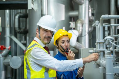 Büyük sanayi fabrikasındaki modern bir termik santralin kontrol odasında çalışan elektrik mühendisi..