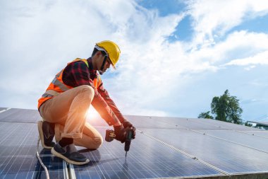 Güneş enerjisi santrali, güneş paneli ve alternatif elektrik kaynağının çatısına sondaj ve bakım güneş panelleri kuran güneş paneli teknisyeni.