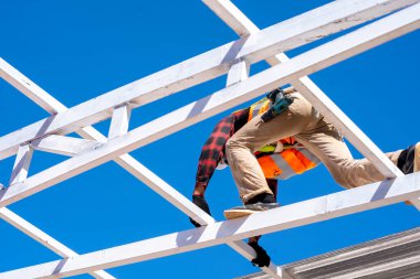 Roofer worker in protective uniform wear installing metal roof on top of the new roof,Concept of residential building under construction,Working on height.