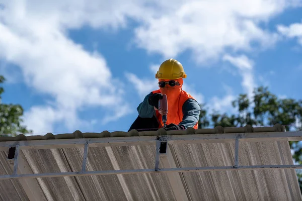 The Roofer technicians work and installing new roof structure on top roof of house,metal roof,fasteners corrugated sheets.