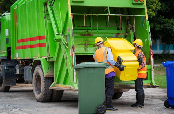 Garbage collection service,Rubbish cleaner man in a uniform working together on emptying dustbins for trash removal with truck loading waste and trash bin,Recycling concept.