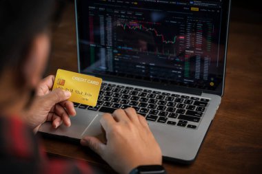 Adamın elinde kredi kartı var ve dizüstü bilgisayar ya da akıllı telefon kullanıyor Online alışveriş sitesi, kartla ödeme işlemi, Smartphone 'dan Easy Etrade web sitesi dükkanı Online. Online alışveriş konsepti. 