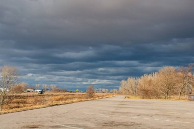 Otobanın üzerindeki güzel koyu mavi gökyüzü. Alışılmadık bir gökyüzü, yapraksız ağaçlar ve fırtınadan önceki bir sonbahar gününde asfalt bir yol. Pacific Junction, IA, ABD, 11-30-2019
