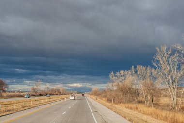 Otobanın üzerindeki güzel koyu mavi gökyüzü. Alışılmadık bir gökyüzü, yapraksız ağaçlar ve fırtınadan önceki bir sonbahar gününde asfalt bir yol. Pacific Junction, IA, ABD, 11-30-2019